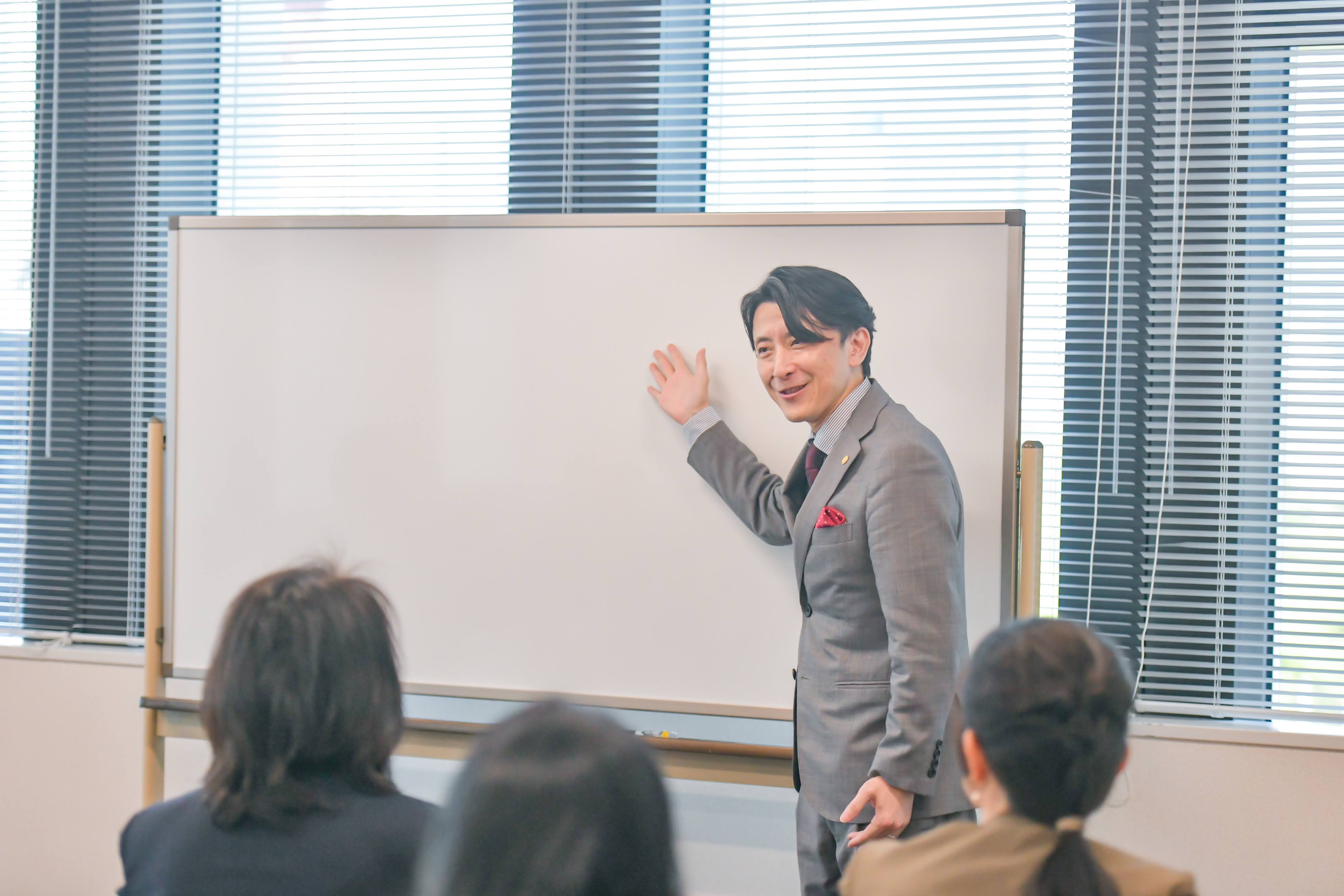 ホワイトボードの前で講義する秋山康二郎